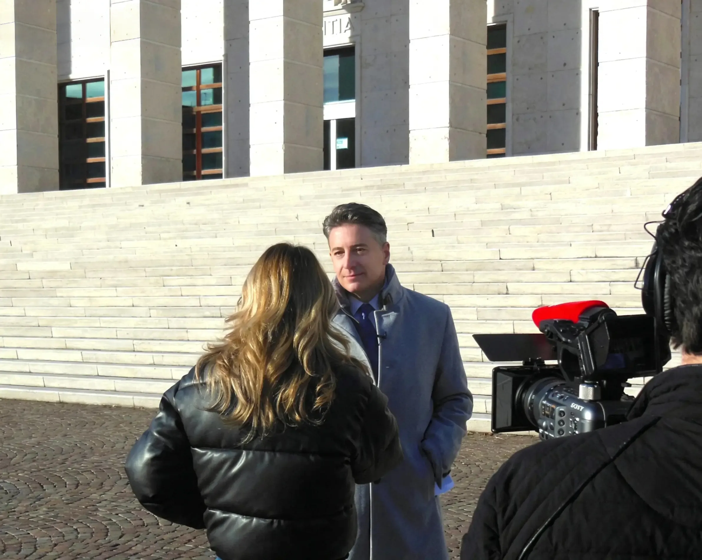 Avvocato Tiziano Pallozzi intervistato da una giornalista e dalle telecamere all'uscita del Tribunale di Bolzano